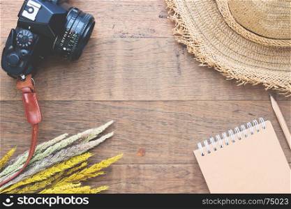 Creative flat lay of Autumn concept with dried flowers, camera, straw hat and notebook on wood background