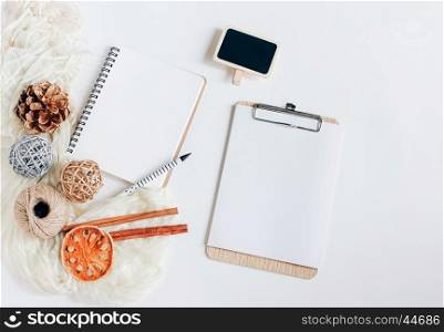 Creative flat lay of blank notebook and clipboard with autumn ornaments on white background, top view