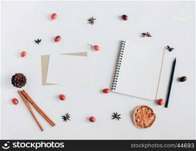 Creative flat lay of blank notebook and greeting card with autumn ornaments on white background, top view