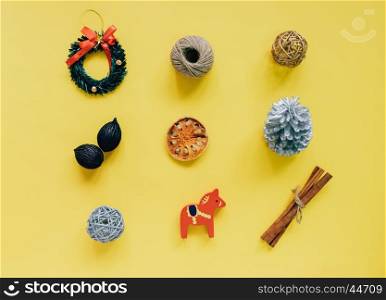 Creative flat lay of christmas ornaments in minimal style on yellow background, top view