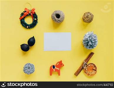Creative flat lay of christmas ornaments in minimal style with blank greeting card on yellow background