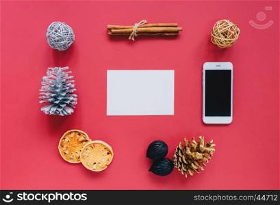 Creative flat lay of christmas ornaments in minimal style with blank greeting card on red background
