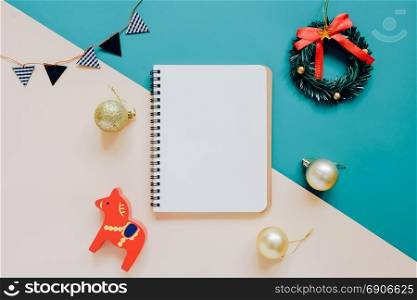 Creative flat lay of craft and blank notebook mock up with christmas ornaments on colorful background, minimal style