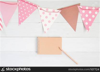 Creative flat lay of craft flag in pastel color with craft paper notebook and pencil, Party invitation card