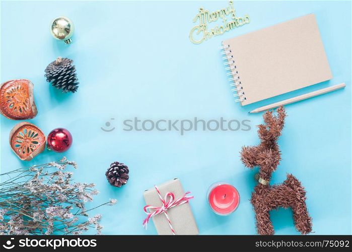 Creative flat lay of craft notebook, Christmas ornaments and gift boxes on pastel color background with copy space