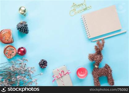 Creative flat lay of craft notebook, Christmas ornaments and gift boxes on pastel color background with copy space