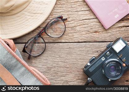 Creative flat lay of eyeglasses, hat, bag, camera and passport on wooden texture background, Travel vacation concept