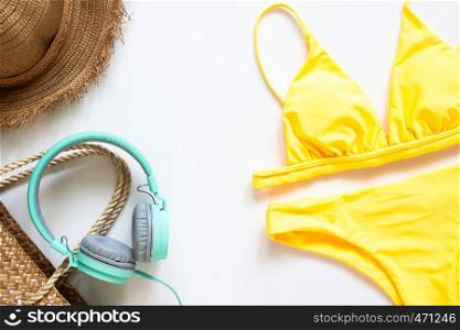 Creative flat lay of summer concept with trendy swimwear, straw hat , bag and headphone on white background.