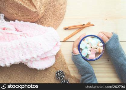 Creative flat lay of woman hands holding a cup hot chocolate with marshmallows topping, Vintage style filter