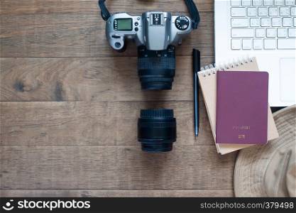 Creative flat lay of workspace desk with film camera, laptop and passport on wooden background. Lifestyle and Travel concept