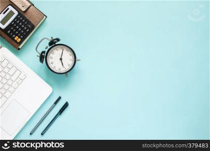 Creative flat lay of workspace desk with laptop, caculator and notebook on blue colour background. Business, Insurance or money concept