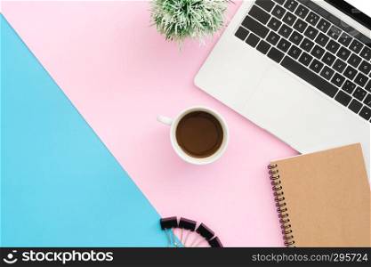 Creative flat lay photo of workspace desk. Top view office desk with laptop, clip, notebook, coffee cup and plant on blue pink color background. Top view with copy space, flat lay photography.