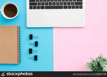 Creative flat lay photo of workspace desk. Top view office desk with laptop, clip, notebook, coffee cup and plant on blue pink color background. Top view with copy space, flat lay photography.
