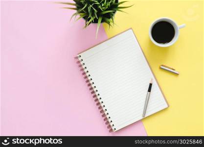 Creative flat lay photo of workspace desk. Top view office desk with mock up notebooks, plant, coffee cup and copy space on pastel color background. Top view with copy space, flat lay photography.