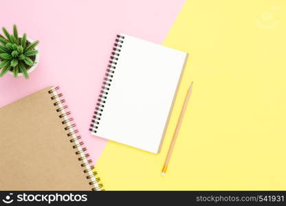 Creative flat lay photo of workspace desk. Top view office desk with open mock up notebooks and pencil and plant on pink yellow pastel color background. Top view with copy space, flat lay photography.