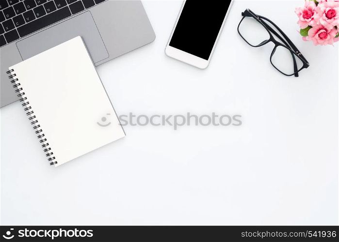 Creative flat lay photo of workspace desk. Top view office desk with laptop, glasses, phone, notebook and plant on white color background. Top view with copy space, flat lay photography.