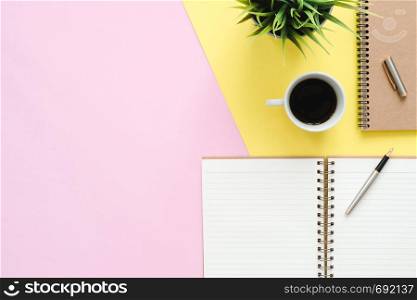 Creative flat lay photo of workspace desk. Top view office desk with mock up notebooks, plant, coffee cup and copy space on pastel color background. Top view with copy space, flat lay photography.