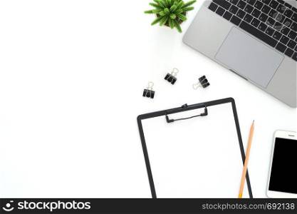 Creative flat lay photo of workspace desk. Top view office desk with laptop, phone, pencil, blank clipboard and plant on white color background. Top view with copy space, flat lay photography.