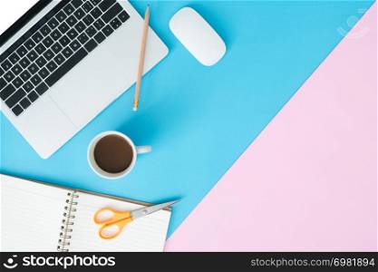 Creative flat lay photo of workspace desk. Top view office desk with laptop, pencil, notebook, coffee cup and mouse on blue pink color background. Top view with copy space, flat lay photography.