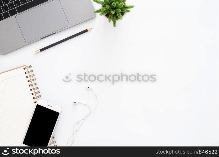 Creative flat lay photo of workspace desk. Top view office desk with laptop, phone, pencil, notebook and plant on white color background. Top view with copy space, flat lay photography.