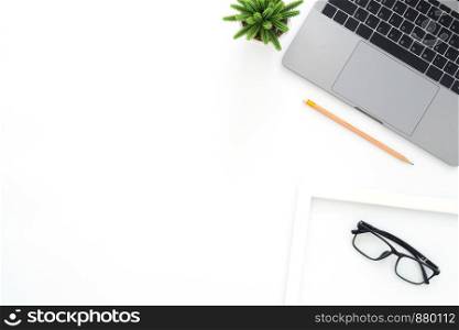 Creative flat lay photo of workspace desk. Top view office desk with laptop, glasses, pencil and plant on white color background. Top view with copy space, flat lay photography.