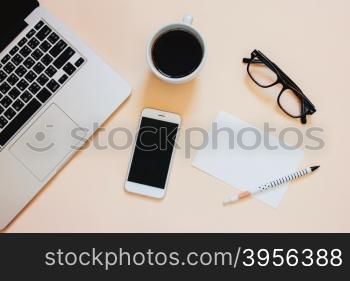 Creative flat lay photo of workspace desk with laptop, smartphone, coffee and blank paper with copy space background, minimal style&#xA;