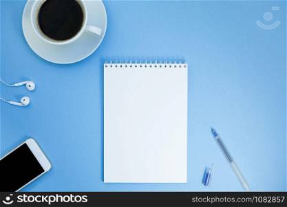 Creative flat lay photo of workspace desk with paper notebook, smartphone, earpieces, pen and coffee with copy space background minimal style