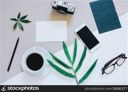 Creative flat lay photo of workspace desk with smartphone, coffee, film camera, blank paper and envelope with copy space background, minimal style&#xD;