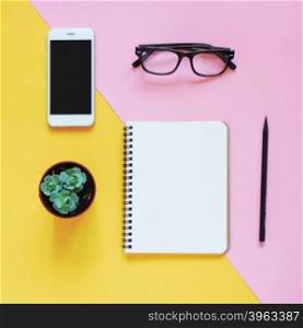 Creative flat lay photo of workspace desk with smartphone, eyeglasses, cactus and notebook with copy space background, minimal style&#xD;
