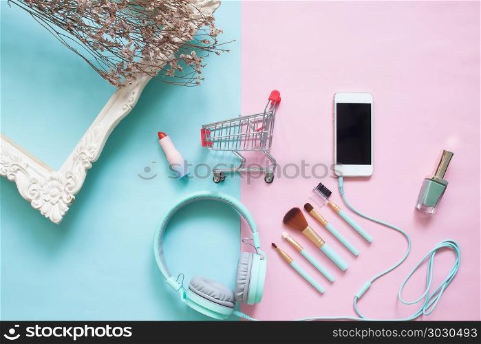 Creative flat lay shopping cart with smartphones and beauty item. Creative flat lay shopping cart with smartphones and beauty items on pastel color background, Beauty and cosmetic, Online shopping