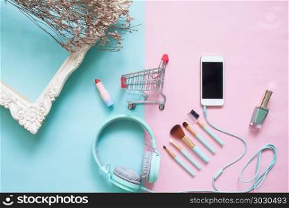 Creative flat lay shopping cart with smartphones and beauty item. Creative flat lay shopping cart with smartphones and beauty items on pastel color background, Beauty and cosmetic, Online shopping
