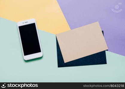 Creative flat lay style workspace desk with smartphone and blank envelope on modern colorful background