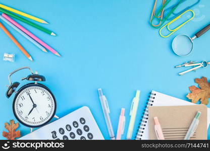 Creative flat lay top view back to school concept with alarm clock, color school and office supplies on bright turquoise paper table frame background with copy space, template for text or design