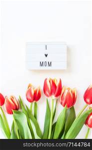 Creative flat lay top view Mothers Day greeting card with red tulips spring flowers on white background. Celebration Postcard template