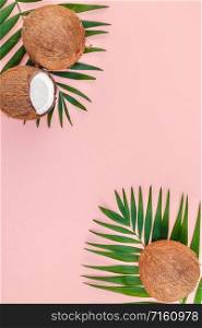 Creative flat lay top view of green tropical palm leaves coconut fruits and coconut oil cosmetics for skin and hair care on pink paper background copy space. Minimal tropical summer beauty spa concept