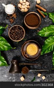 Creative flat lay with coffee, milk, sugar and tropical leaves on dark rustic background, copyspace. Coffee composition on dark rustic background, flat lay, top view
