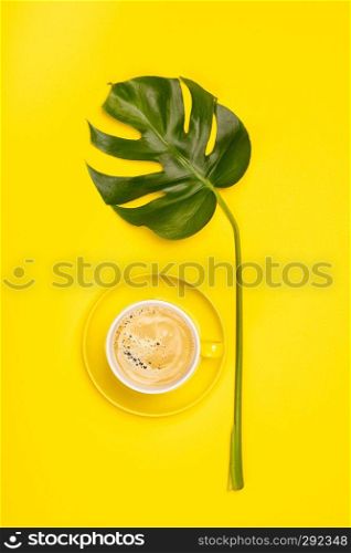 Creative flat lay with cup of coffee and tropical plant on yellow background. Creative flat lay with cup of coffee and tropical plant