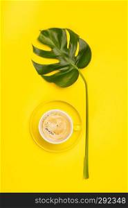 Creative flat lay with cup of coffee and tropical plant on yellow background. Creative flat lay with cup of coffee and tropical plant