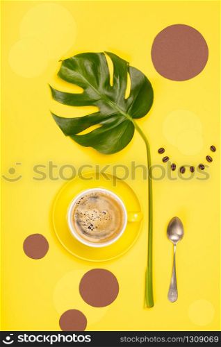 Creative flat lay with cup of coffee, paper circles and tropical plant on yellow background. Creative flat lay with cup of coffee and tropical plant