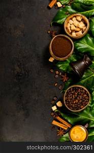 Creative flat lay with milled coffee, coffee beans, brown sugar and tropical leaves on dark rustic background, copyspace. Coffee composition on dark rustic background, flat lay, top view