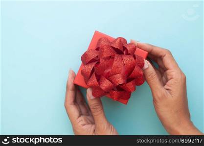 Creative flat lay woman hand holding beautiful red gift box on pastel colour background