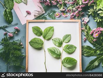 Creative florist workspace with flowers , greeting card mock up and beautiful green leaves for arrangement , top view, flat lay
