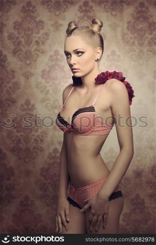 creative glamour portrait of charming young girl with blonde trendy hairdo wearing sexy pink lingerie and some red flowers on the shoulders .vintage halloween