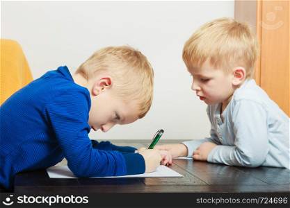 Creative hobby, kids passion concept. Two boys playing together, drawing pictures on paper. Kids playing together, drawing pictures on paper