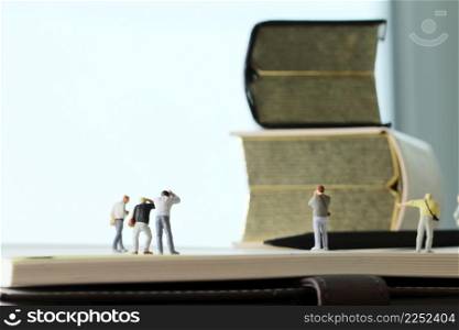 Creative idea concept - miniature photographer with vintage golden book on open paper notebook