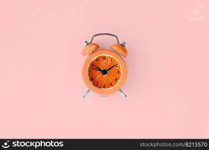 Creative idea fresh grapefruit slice alarm clock on pastel orange background. Minimal business concept. Fruit idea creative to produce work within advertising marketing solutions. Fresh grapefruit slice in small orange alarm clock