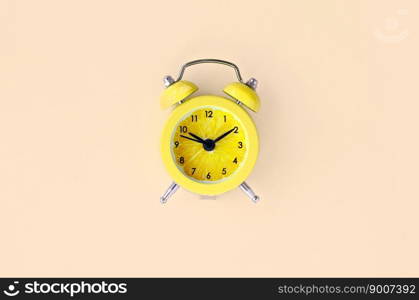 Creative idea fresh lemon slice alarm clock on pastel yellow background. Minimal business concept. Fruit idea creative to produce work within advertising marketing solutions. Fresh lemon slice in small yellow alarm clock