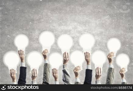 Creative ideas. Many human hands holding light bulb signs