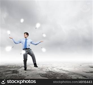 Creative ideas. Young handsome businessman juggling with electrical bulb