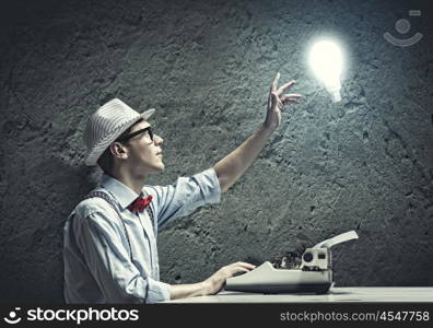 Creative inspiration. Young funny man in glasses writing on typewriter